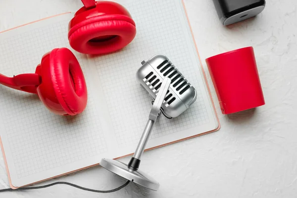 Headphones with microphone, notebook and speaker on white background