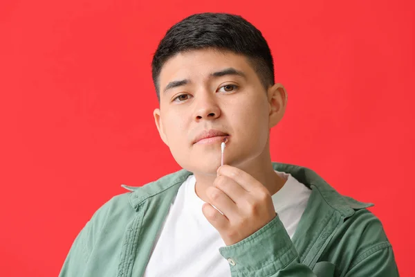 Asiatisk Man Med Munsår Tillämpa Salva Läpparna Mot Färg Bakgrund — Stockfoto