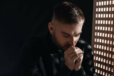 Günah çıkarma kabinindeki genç rahip.