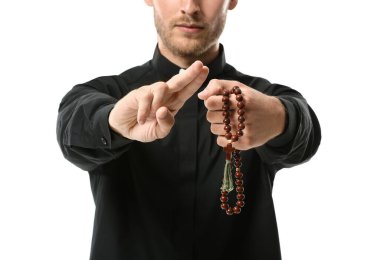 Beyaz arka planda tespihi olan yakışıklı bir rahip.