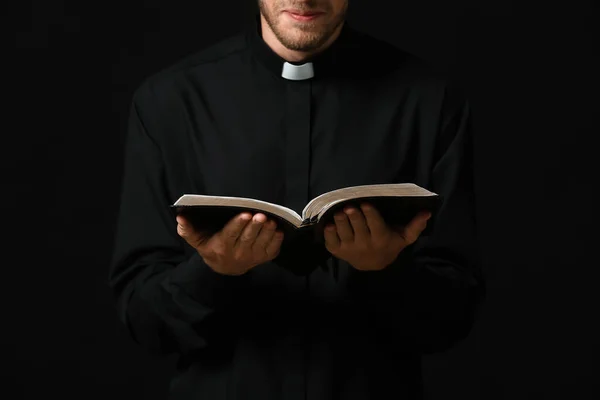 Schöner Priester Mit Bibel Auf Dunklem Hintergrund — Stockfoto