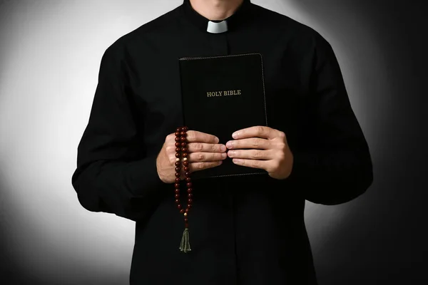 Schöner Priester Mit Bibel Auf Dunklem Hintergrund — Stockfoto