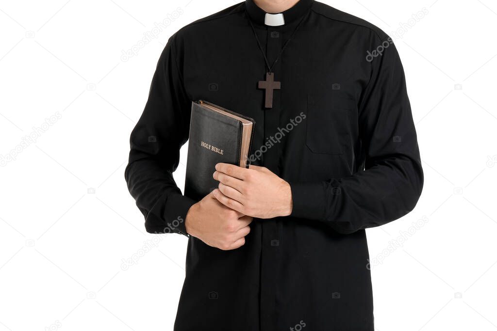 Handsome priest with Bible on white background