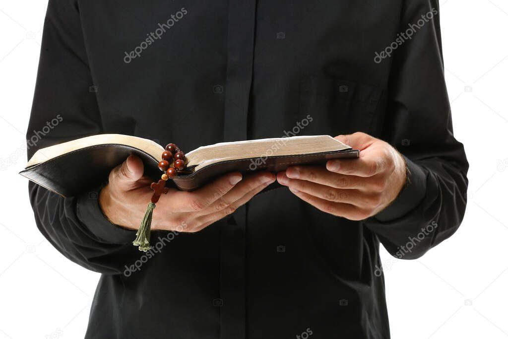 Handsome priest with Bible on white background, closeup