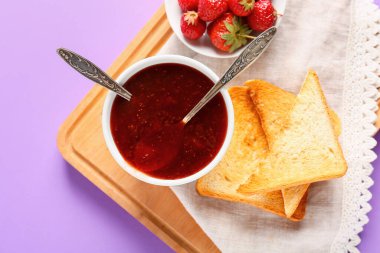 Renkli arkaplanda bir kase lezzetli çilek reçeli ve ekmek