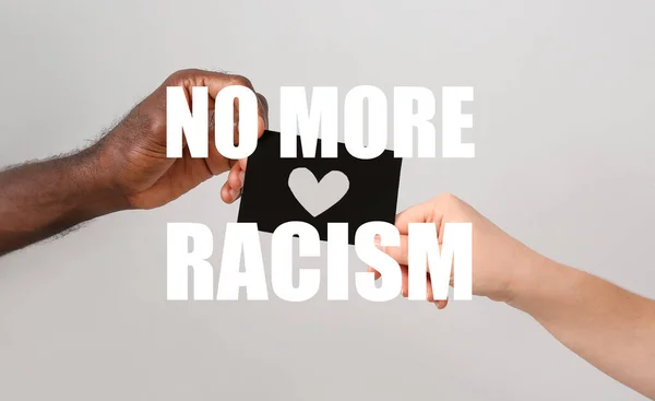 白种人女人和非裔美国男人的手拿着灰色背景的纸片 种族主义的概念 — 图库照片