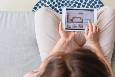 Evindeki otelde tablet bilgisayarlı rezervasyon odası olan kadın.