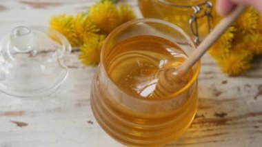 Karahindiba balı kadın kavanozda ve masada kaşık