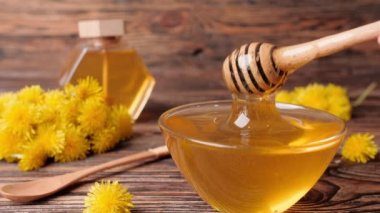 Tahta masada bal ve kaşıkla karahindiba tabağı