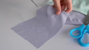 Atölyede kumaş kesen kadın terzi, yakın plan.