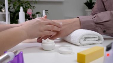 Manikür ustası erkek müşteriyle güzellik salonunda çalışıyor.