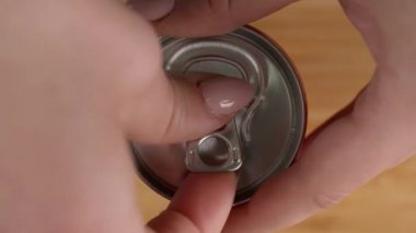 Kadın konserve kutusunu masada açıyor, yakın plan.