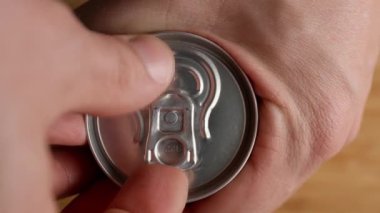 Adam konserve kutusunu masada açıyor, yakın plan.