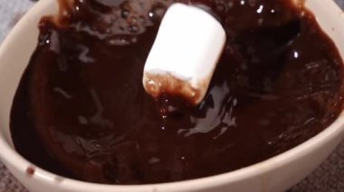 Lezzetli marşmelovu sıcak kakao bardağına damlatarak.