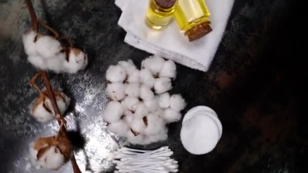 暗い背景に綿の花 きれいなタオル 綿パッド スワブと綿の種子油でテーブルを回転させ トップビュー — ストック動画