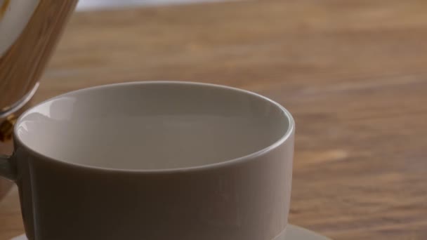 Verser du café chaud de la casserole dans une tasse sur la table, gros plan