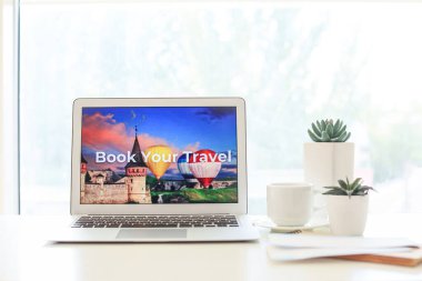 Masadaki dizüstü bilgisayarın ekranında çevrimiçi rezervasyon servisinin sayfasını aç