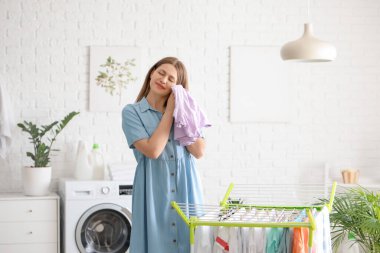 Çamaşır odasında temiz çamaşırları kurutucuya asan bir kadın.