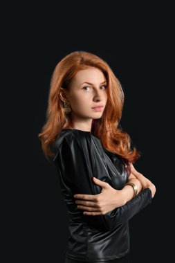 Koyu arkaplanda güzel kızıl saçlı bir kadın.