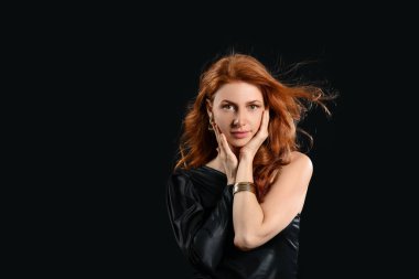 Koyu arkaplanda güzel kızıl saçlı bir kadın.