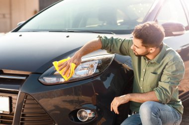 Adam dışarıda arabasını yıkıyor.