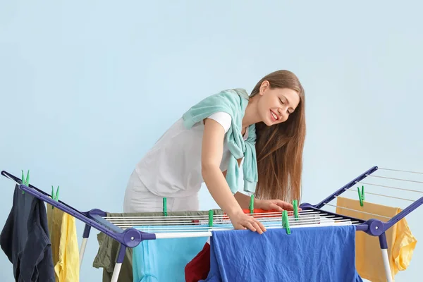 女人把干净的衣服挂在烘干机上 衬托着彩色背景 — 图库照片