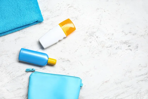 Beyaz arka planda güneş kremi ve havlu olan çanta.