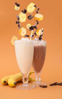 Renkli arka planda lezzetli milkshake bardakları ve dökülen malzemeler