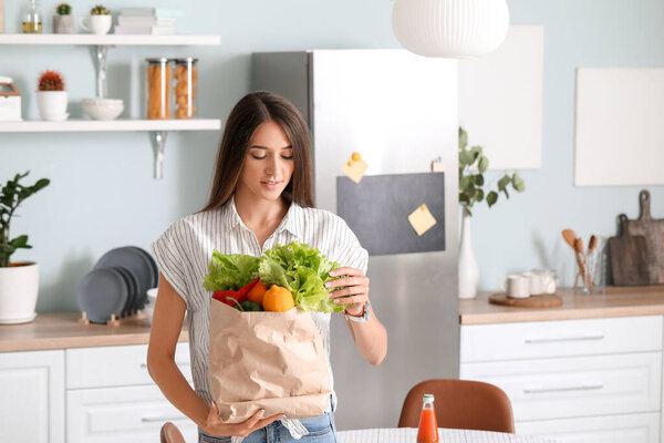 Young woman with fresh products from market at home