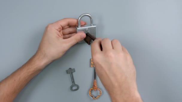 Mann Wählt Schlüssel Zum Öffnen Des Vorhängeschlosses Auf Grauem Hintergrund — Stockvideo