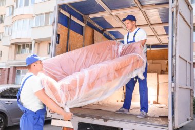 Yükleyiciler kamyondan mobilya alıyor.