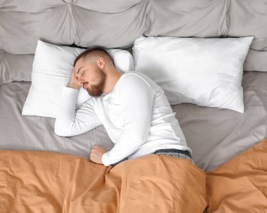 Genç adam yatağında uyuyor.