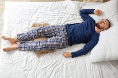 Genç adam yatağında uyuyor.