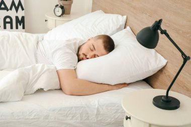 Genç adam yatağında uyuyor.