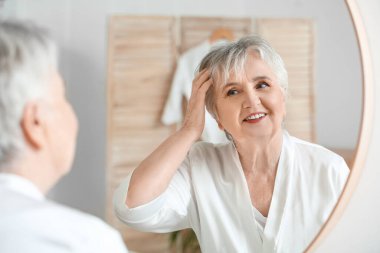 Evdeki aynaya bakan kıdemli kadın.