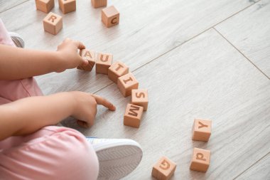 Otistik bozukluğu olan küçük bir kız yerde küplerle oynuyor.