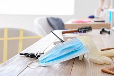 Coronavirus salgını sırasında kuaför salonundaki masada lastik eldivenli tıbbi koruyucu maske.