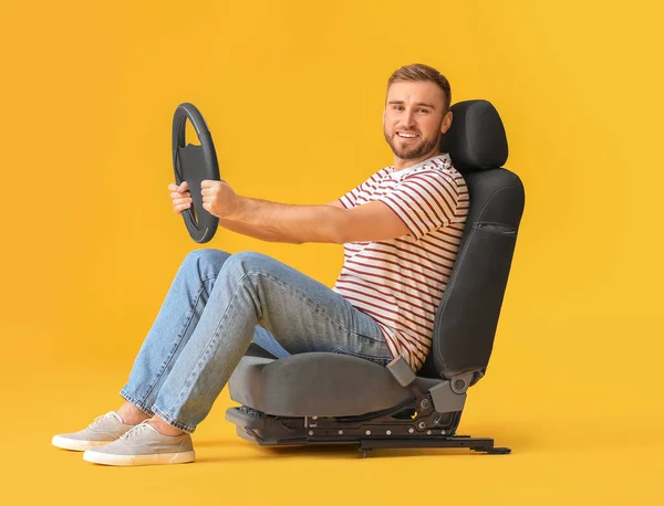 Junger Mann Mit Lenkrad Sitzt Auf Autositz Vor Farbigem Hintergrund — Stockfoto