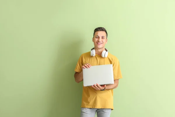 Male programmer with laptop on color background