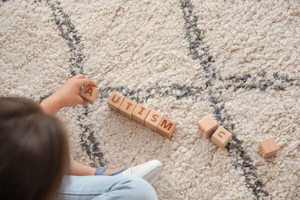 Маленькая девочка с аутизмом играет с кубиками дома