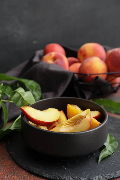 Bowl with cut ripe peaches on table