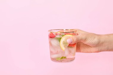 Renkli arkaplanda taze çilekli limonata dolu bir el.