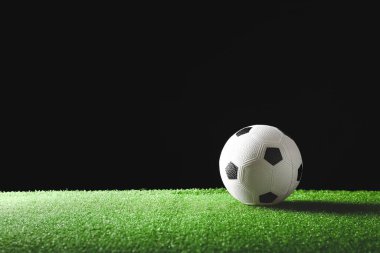 Koyu arkaplana karşı yeşil sahada futbol topu