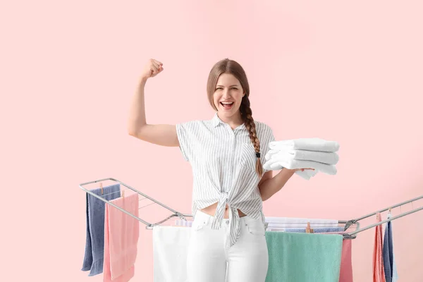 女人把干净的毛巾挂在烘干机上 衬托着彩色背景 — 图库照片