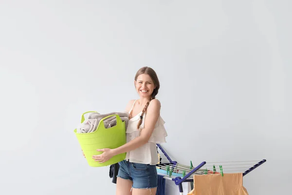 有干净衣服和浅色背景干衣机的女人 — 图库照片