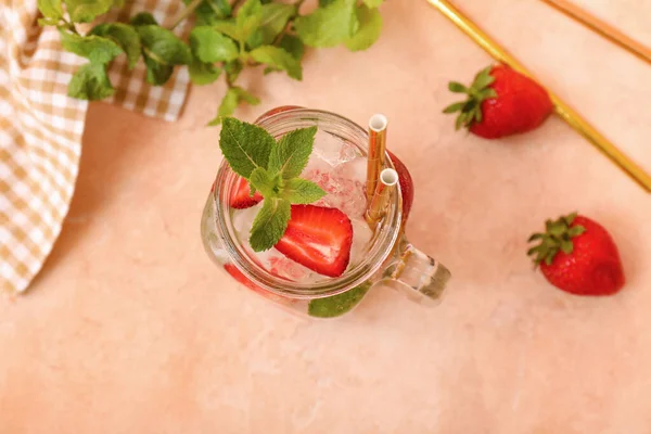 Mason jar of fresh strawberry lemonade on color background