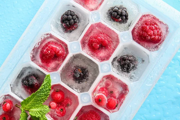 Tray with berries in ice on color background, closeup
