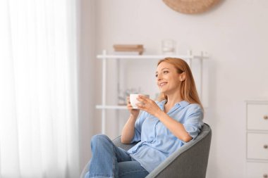 Evde çay içen güzel bir kadın.