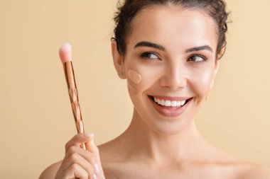 Yüzünde temeli olan güzel, genç bir kadın.