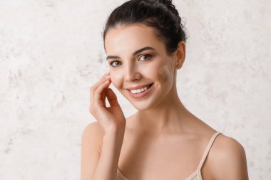 Yüzünde temeli parlak arka planda olan güzel genç bir kadın.